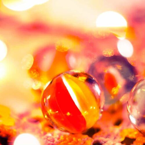 Colorful marbles in use on a vibrant, bokeh light background.