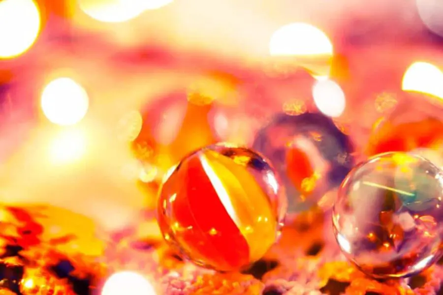 Colorful marbles in use on a vibrant, bokeh light background.