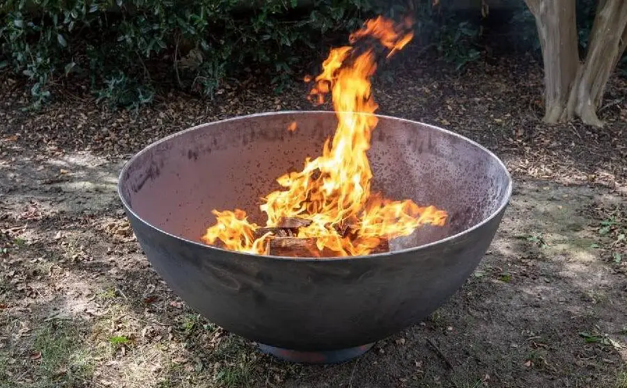 A fire burning in a large outdoor metal fire bowl.