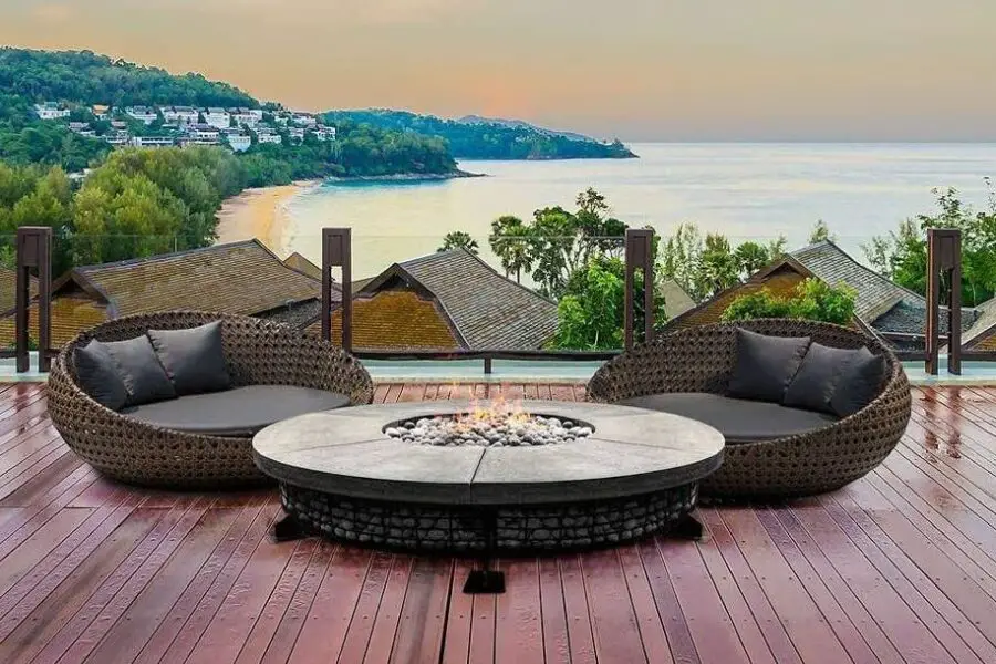 Luxurious outdoor lounge area with two circular sofas and a luxury fire pit overlooking a tranquil beachscape.