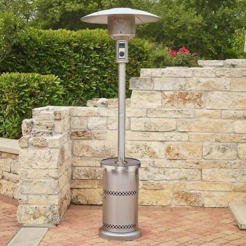 Patio heater standing on a brick pavement near a stone wall with plants, ready for use indoors.