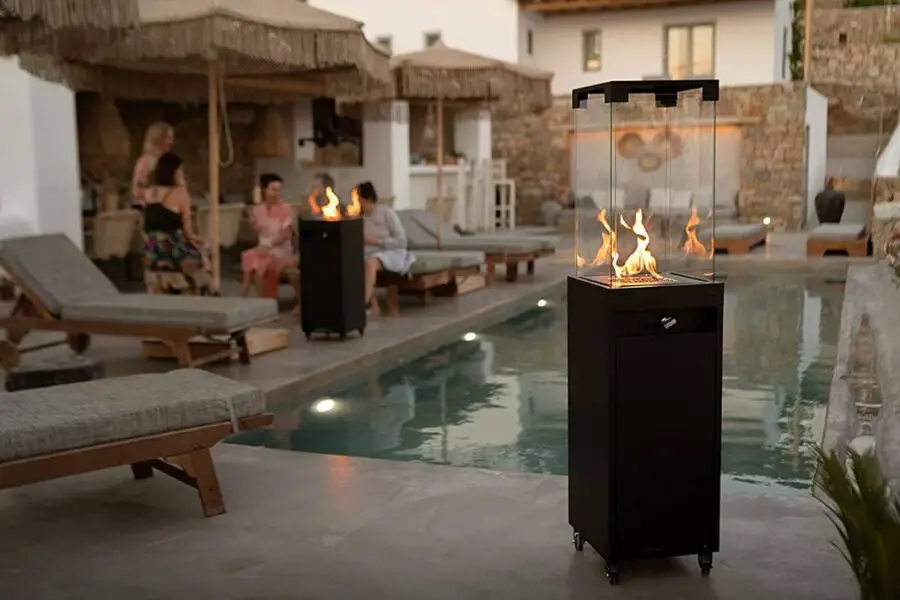 An outdoor patio heater by a poolside with people relaxing in the background.