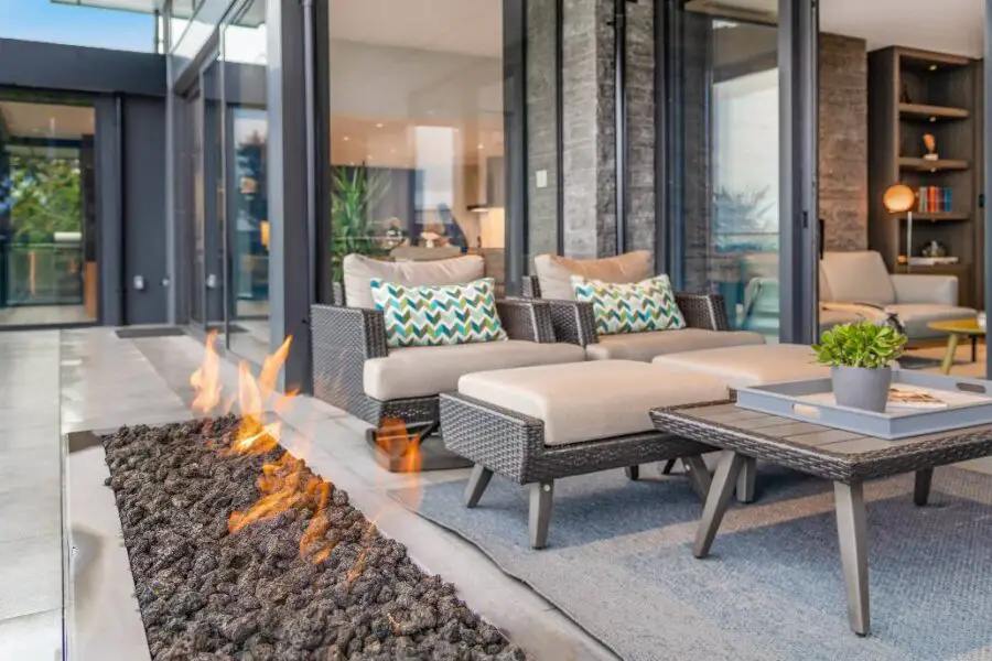 Modern outdoor patio of needed size with fire pit and view into stylish interior.