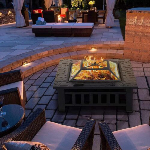 An outdoor patio with a lit fire pit in use and seating arrangement at dusk.