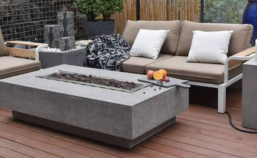 A modern outdoor patio area with a gas fire pit table undergoing repair, comfortable seating, and decorative elements.