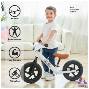 A young boy proudly standing with his balance bike, showcasing its benefits for balance, independence, leg strength, and riding fun.