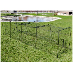 A metal fence forming a temporary enclosure on a grassy park area with a pond in the background.