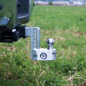 A silver adjustable Weigh Safe Aluminum Drop Hitch with a ball mount is attached to a vehicle, positioned in a grassy field.
