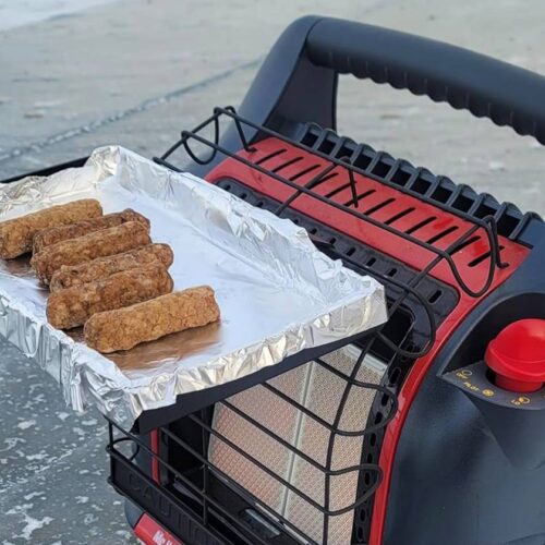 A small portable heater with a wire rack is toasting several sausages on top of a foil tray, perfect for those chilly ice fishing days inside an ice fishing tent.