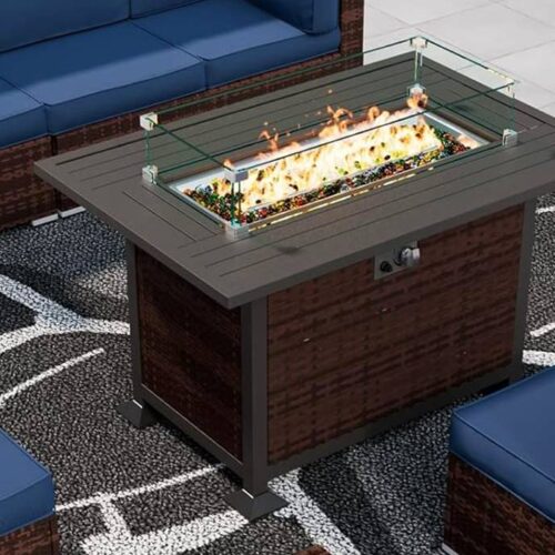 This outdoor patio set, a must-have for outdoor get-togethers, features a wicker fire pit table surrounded by a sofa, two chairs, and an ottoman with blue cushions. All are placed on a patterned rug near the swimming pool—perfect cozy fire pit furniture for any occasion.